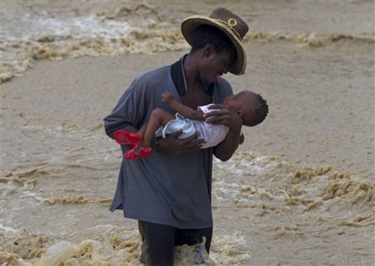 A man carries a child while wading across a flooded street during the passing of Hurricane Tomas in Leogane, Haiti, on Friday. 